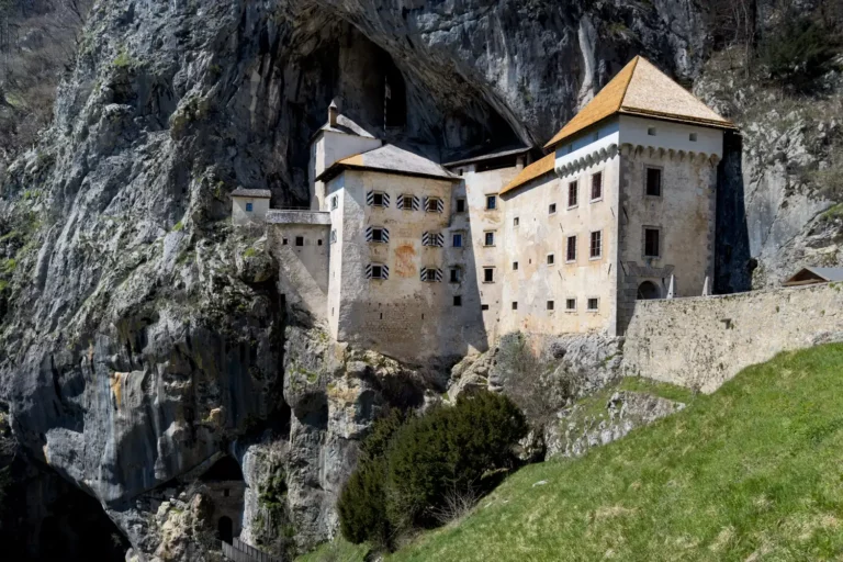 Burg Predjama, eine beeindruckende Festung, die in eine Felswand integriert ist, mit historischen Gebäuden und einem markanten Dach.